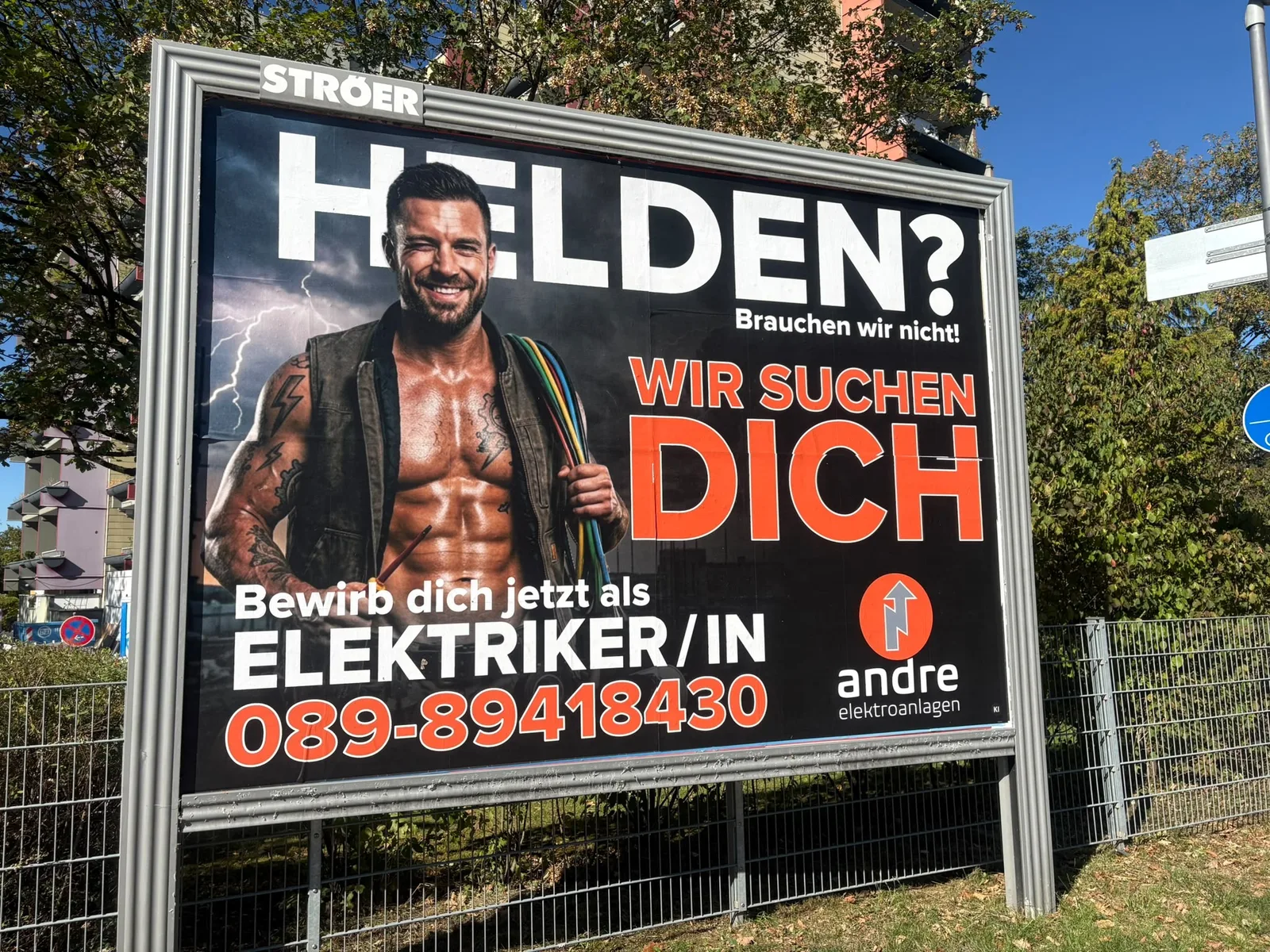 Großflächenplakat von Andre Elektroanlagen an einer Straße in Germering mit dem Motiv Helden? Brauchen wir nicht! Wir suchen Dich.